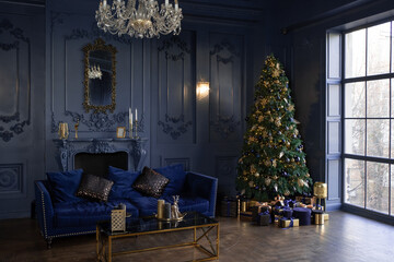 Large living room with panoramic windows and blue walls. Christmas decor in the hall. Christmas tree near sofa and fireplace