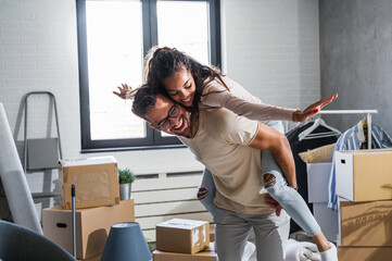 Happy multiethnic couple just moved into new empty apartment unpacking, having un
