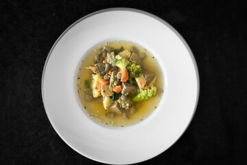 Ein weißer Teller Gemüsesuppe, Hühnersuppe mit Karotten, Leberknödel und Bio Gemüse