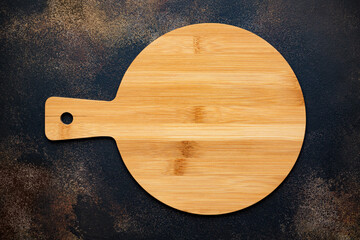 New round wooden cutting board for pizza on stone background. Top view. Mock up for food project.
