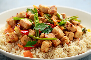 Vegetarian meat free mycoprotein pieces vegetable stir fry, brown rice served in white plate