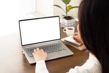 woman hand using laptop with mock up white screen and taking notes. work from home concept. 