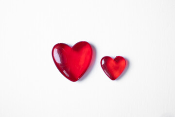 Fototapeta premium Valentine's day background with two red hearts. Shiny glass hearts on white background.