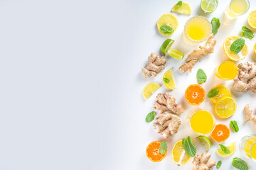 Immunity booster drink ingredients. Homemade ginger and citrus juice or cocktail, with fresh citrus fruit - orange, lemon, lime, with ginger root and mint leaves. White background top view copy space