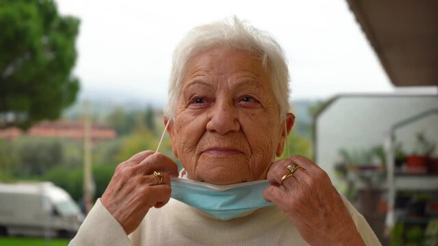 an elderly lady taking off the protective surgical mask