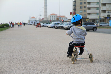 boy pedaling a tricycle with a blue helmet
