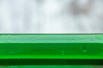 Part of bright green plastic bottle on blurred light background