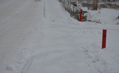 connection of a side dirt road to an asphalt road. the turn is highlighted by a pair of red...