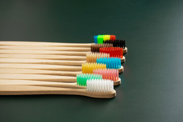 A set of Eco-friendly antibacterial toothbrushes made of bamboo wood on a dark green background. Environmental trends