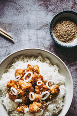 Choux-fleur caramélisé aux graines de sésame et petits oignons accompagné de riz blanc dans une assiette - Plat gourmand asiatique