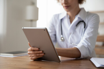 Close up young female general practitioner using digital computer tablet at clinic office., web...