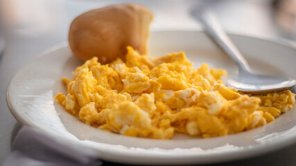 Image of a breakfast with scrambled eggs and bread on a white run plate