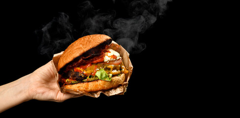 Hands hold big Burger cheeseburger sandwich with marble beef lettuce tomato cheese bacon with steam...