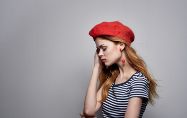Fototapeta premium woman in a red beret and a striped t-shirt on a light background cropped view Copy Space