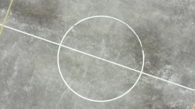 Top view of the circle in the middle of a basketball field; zooming out to reveal the whole field