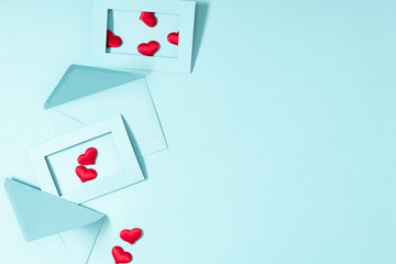 Creative minimal Valentine's Day concept. Envelopes, red hearts confetti, valentines on pastel blue background. Flat lay, top view, copy space