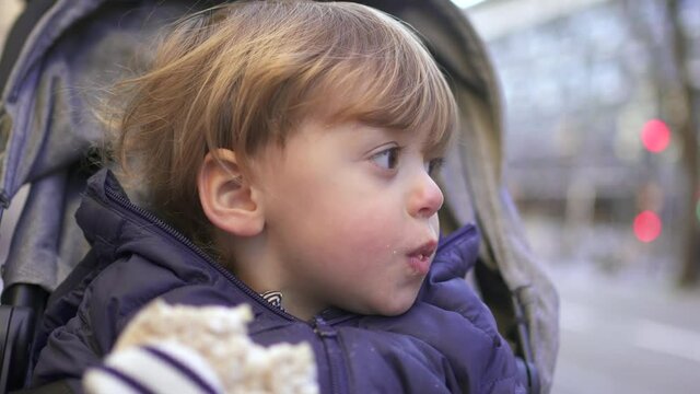 Baby toddler sitting inside stroller on city sidewalk