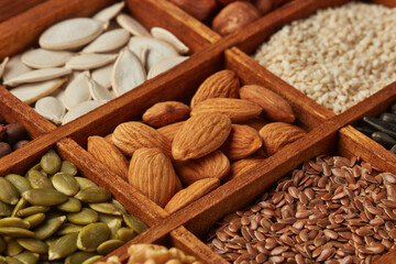 Different kinds of nuts and dried seeds in wooden box on brown wooden background. Top view. Healthy food. Vegetarian nutrition