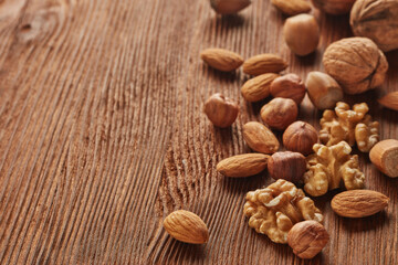 Various types of nuts. Whole nuts and kernels on brown textured wooden background. Selective focus on kernels. Healthy food