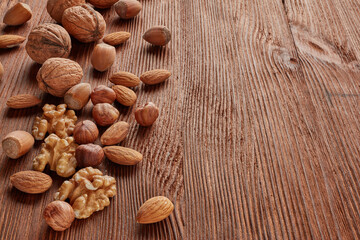 Various types of nuts. Whole nuts and kernels on brown textured wooden background. Top view with copy space. Healthy food