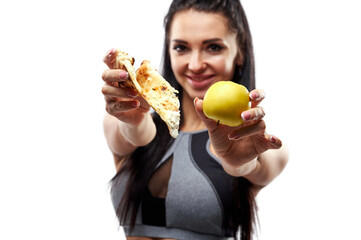 Fit woman holding an apple in one hand and a slice of pizza in the other and showing them to the camera. Focus on food.