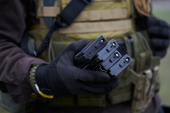 Airsoft player holds magazines for a machine gun in his hand