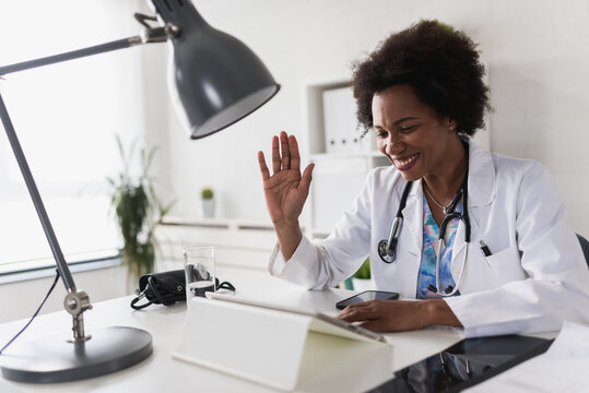 African American woman doctor working at her office doing telemedicine services. Helping patients online and by the phone. Primary care consultations