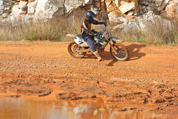 Zoom photo of motocross professional rider in action performing high speed stunts in dirt and mud...