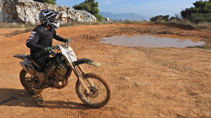 Zoom photo of motocross professional rider in action performing high speed stunts in dirt and mud terrain