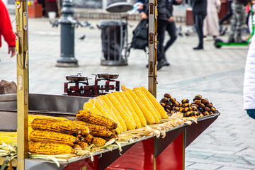 Grilled corn and boiled corn are on the counter at a street vendor.