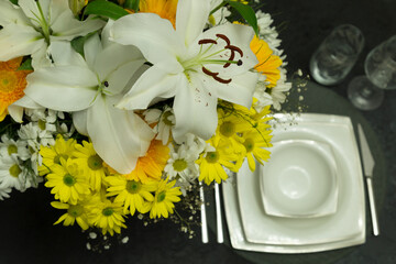 Luxury porcelain dinner set with glass and flowers on the black table.