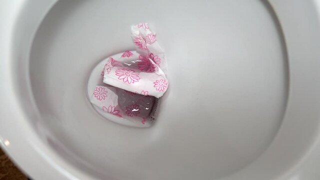 Close-up tossing toilet paper down the toilet. Close-up of flushing the toilet