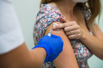 The doctor injects the flu, pneumonia, or COVID-19 vaccine into the patient's shoulder