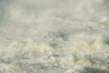 Rough river with seething water with foam and flying splashes and water drops