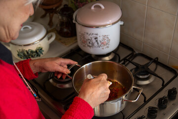 Woman in red sweater cooking soup in the kitchen. Selective focus right hand. Traditional turkish soup tarhana.