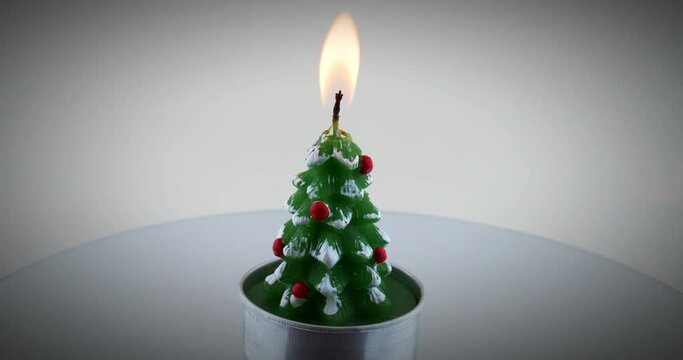 Burning christmas tree shaped tee candle on spinning lazy susan turntable. 4k video