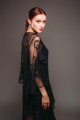 Fototapeta premium Black transparent evening dress. Beautiful model wearing high heels, modern feminine look for an event. Women's fashion. Adorable lady.