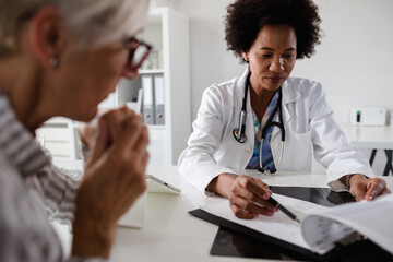 Female doctor looking at test results of her patient. Doctor and patient talking over a medical test result.