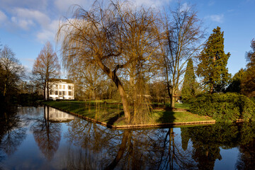 Manor estate Voorstonden and lush garden mirroring in still water in the foreground