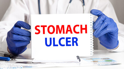 A sheet of paper with text STOMACH ULCER, stethoscope and medical documents on the table. Medical...