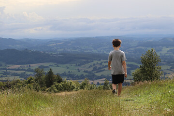Naklejka na ściany i meble Boy walking across the hills in the countryside