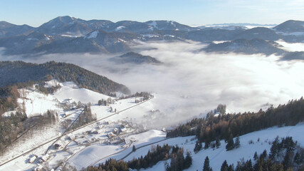 AERIAL: Small village in the serene Julian Alps on a misty winter morning.