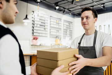 Deliver lunch pizza and pasta to your home in a short time. small business pizzeria coffee shop. a young male employee in an apron picks up the courier. fast delivery in a corrugated cardboard box.