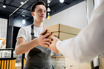 Buys lunch food healthy foods vegetables pasta in a paper bag with a takeaway. a young male employee picks up dinner. convenient durable delivery in a corrugated cardboard box.