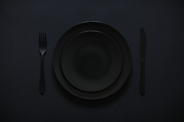Plates nicely served for a meal. Everything is black. Festive lunch concept.