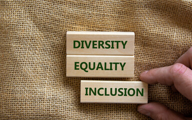Diversity, equality and inclusion symbol. Wooden blocks with words 'diversity, equality and inclusion' on beautiful canvas background. Male hand. Diversity, business, equality and inclusion concept.