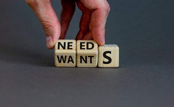 Wants or needs symbol. Hand turns cubes and changes the word 'wants' to 'needs'. Beautiful grey background, copy space. Valentines day and wants or needs concept.