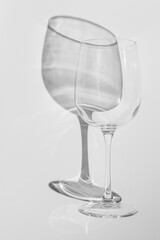 Wine glass lies on white background. Glass with hard shadow in monochrome