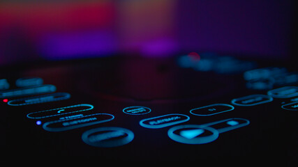Podświetlona stacja DJ, w tle ciepłe, imprezowe kolory. Błękitne, smukłe przyciski urządzenia. - obrazy, fototapety, plakaty