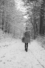Spacerująca urokliwą leśną ścieżką młoda dziewczyna w płaszczu.